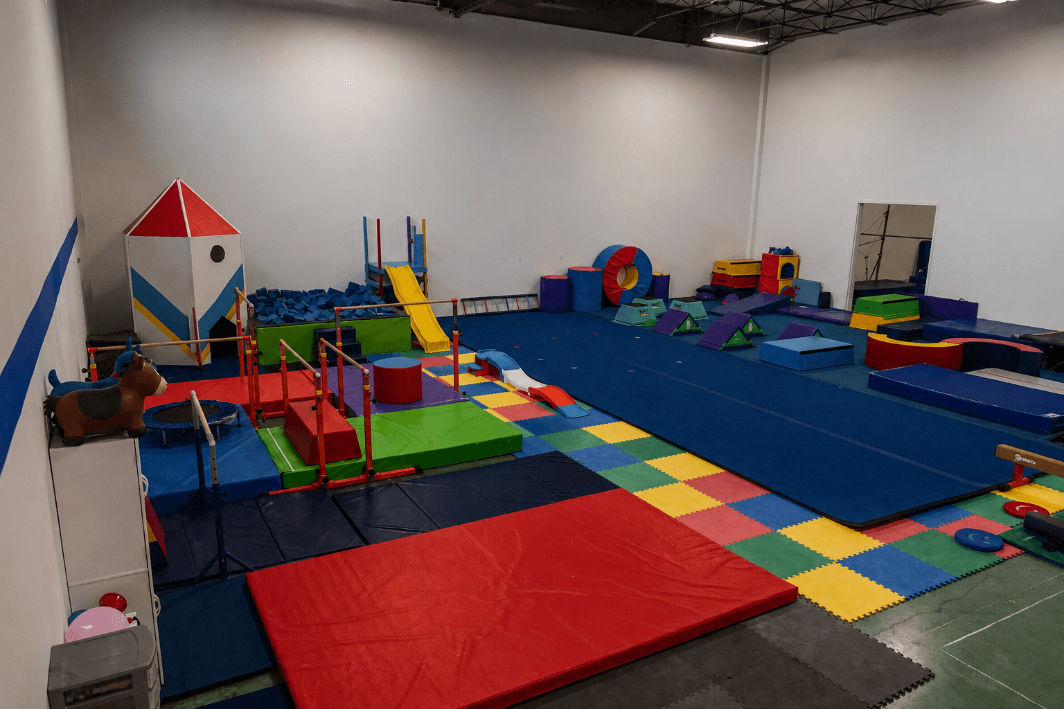 The colorful Little Gym preschool room at Gym Stars, with soft mats, a rocket ship playhouse, and a foam pit