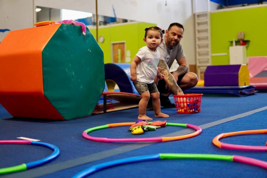 A toddler playing at the Gym Stars front lobby with a parent